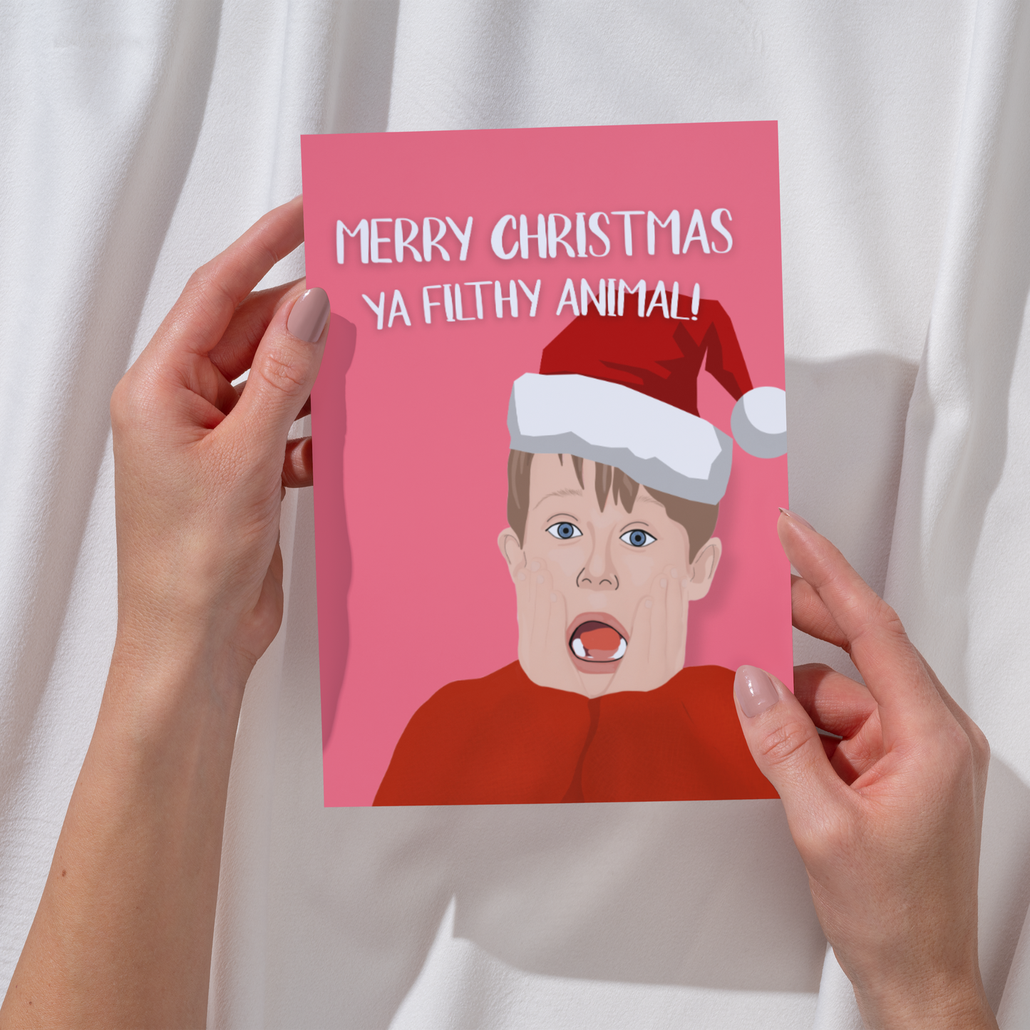 Person holding a Christmas card with kevin mccallister wearing a Santa hat and text on a white background